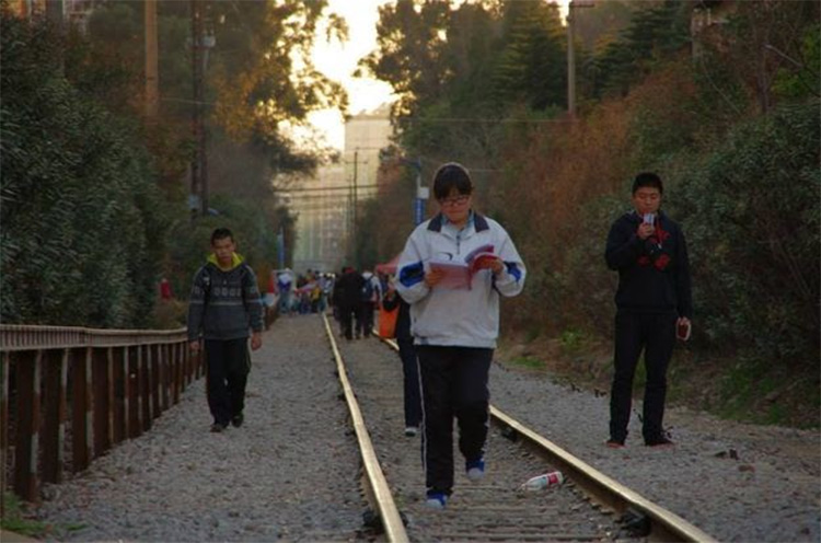 中国雲南省にて。大学構内を通る線路、そしてそこを歩く学生たち